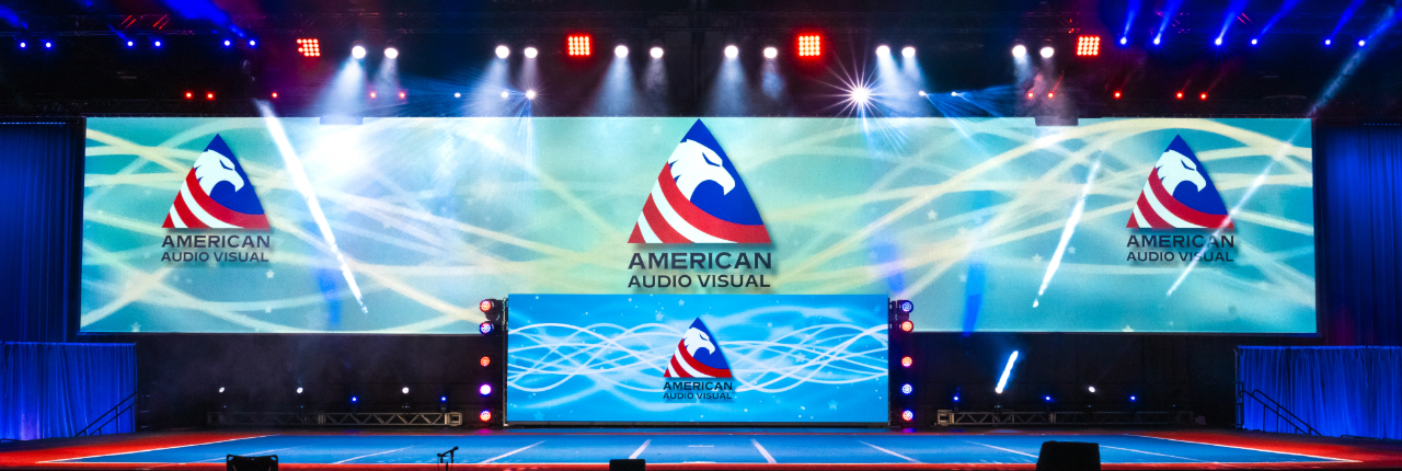 Cheer event stage setup with professional lighting, large video screens, and elegant draping by American Audio Visual.