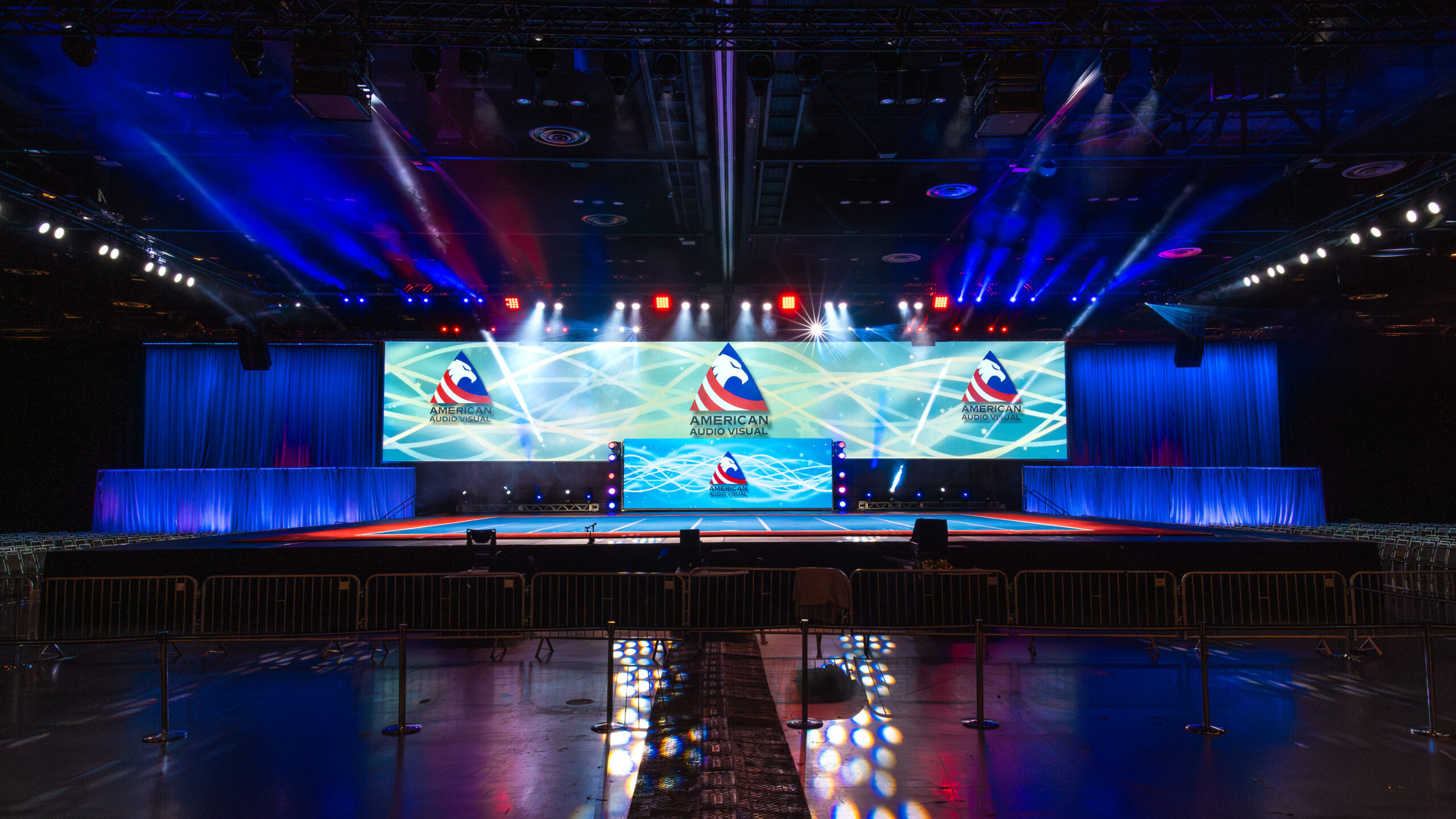 Corporate event stage setup with professional lighting, large video screens, and elegant draping by American Audio Visual.